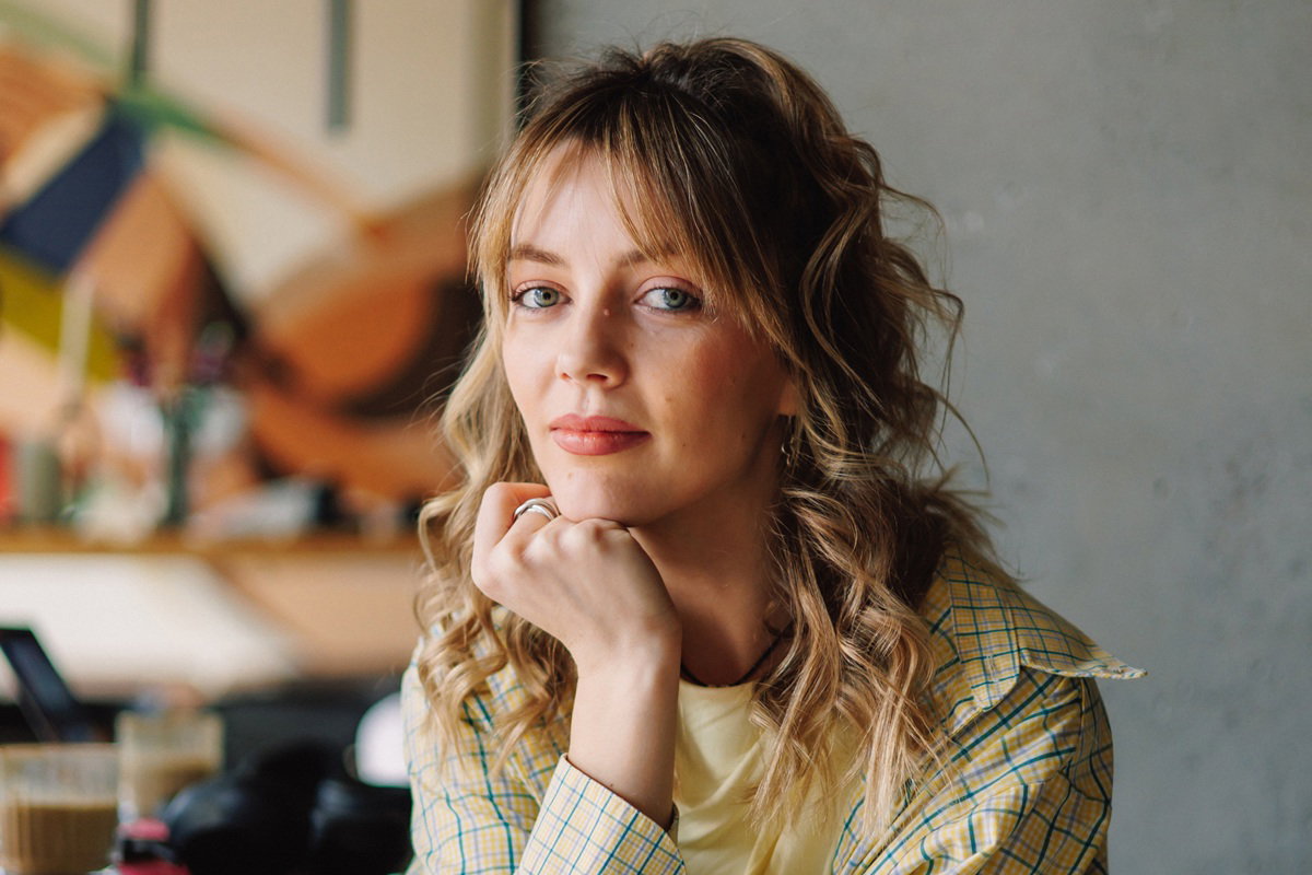 kobieta w wieku 30 plus blondynka kręcone włosy siedzi zamyślona w kawiarni