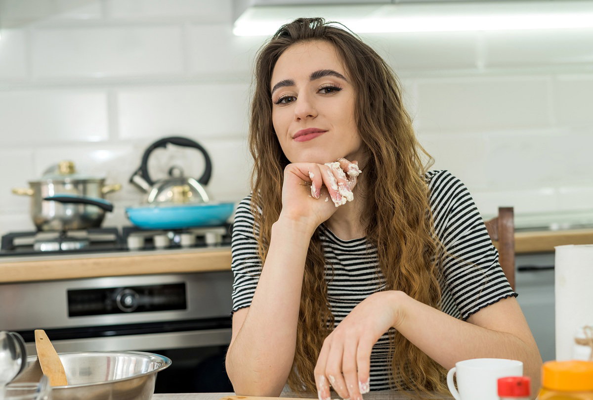 kobieta w wieku 30 plus w bluski w paski siedzi w kuchni zadowolona i ubrudzona mąką