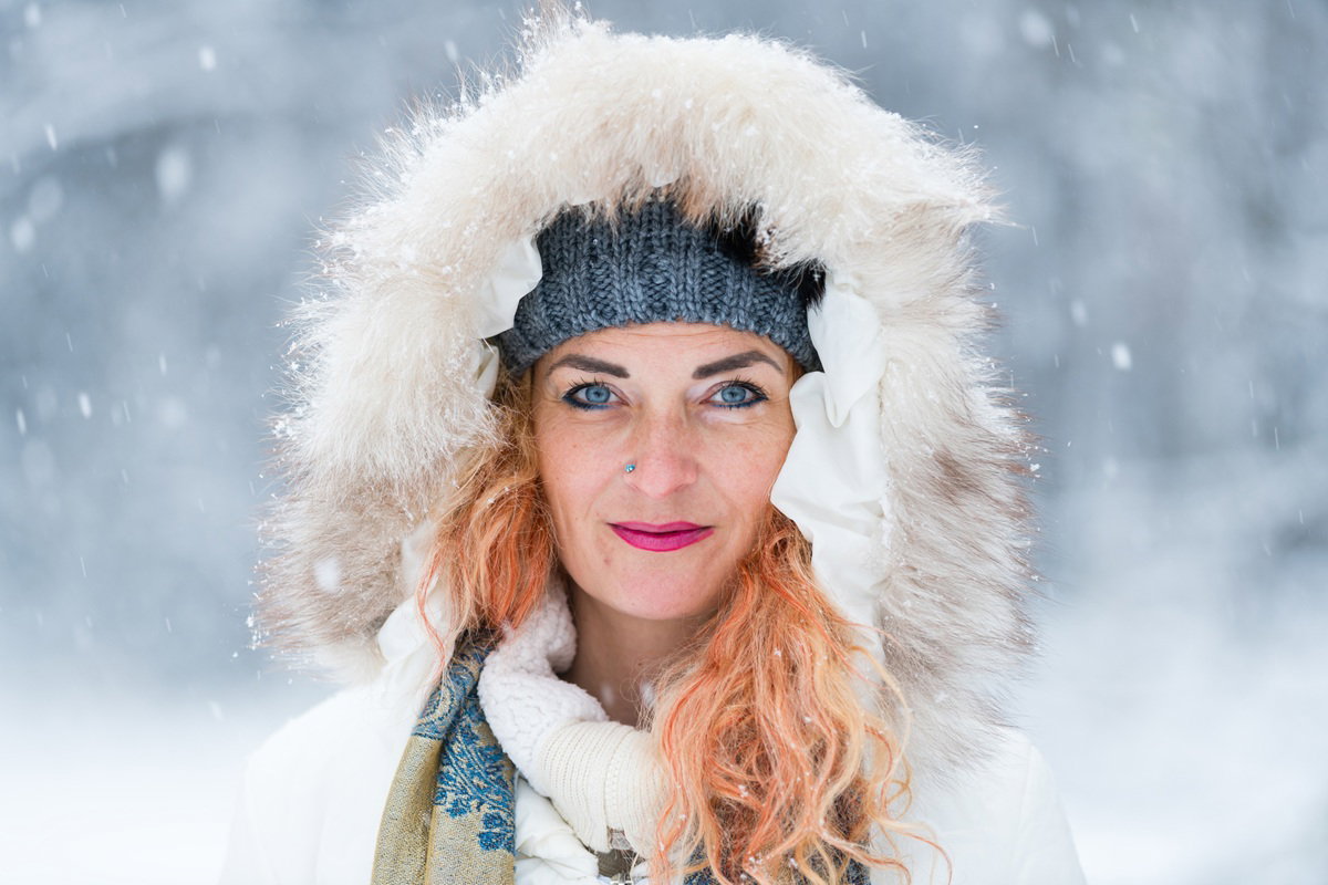 kobieta w wieku 45 plus w kapturze z futerkiem stoi na tle zaśnieżonego pejzażu