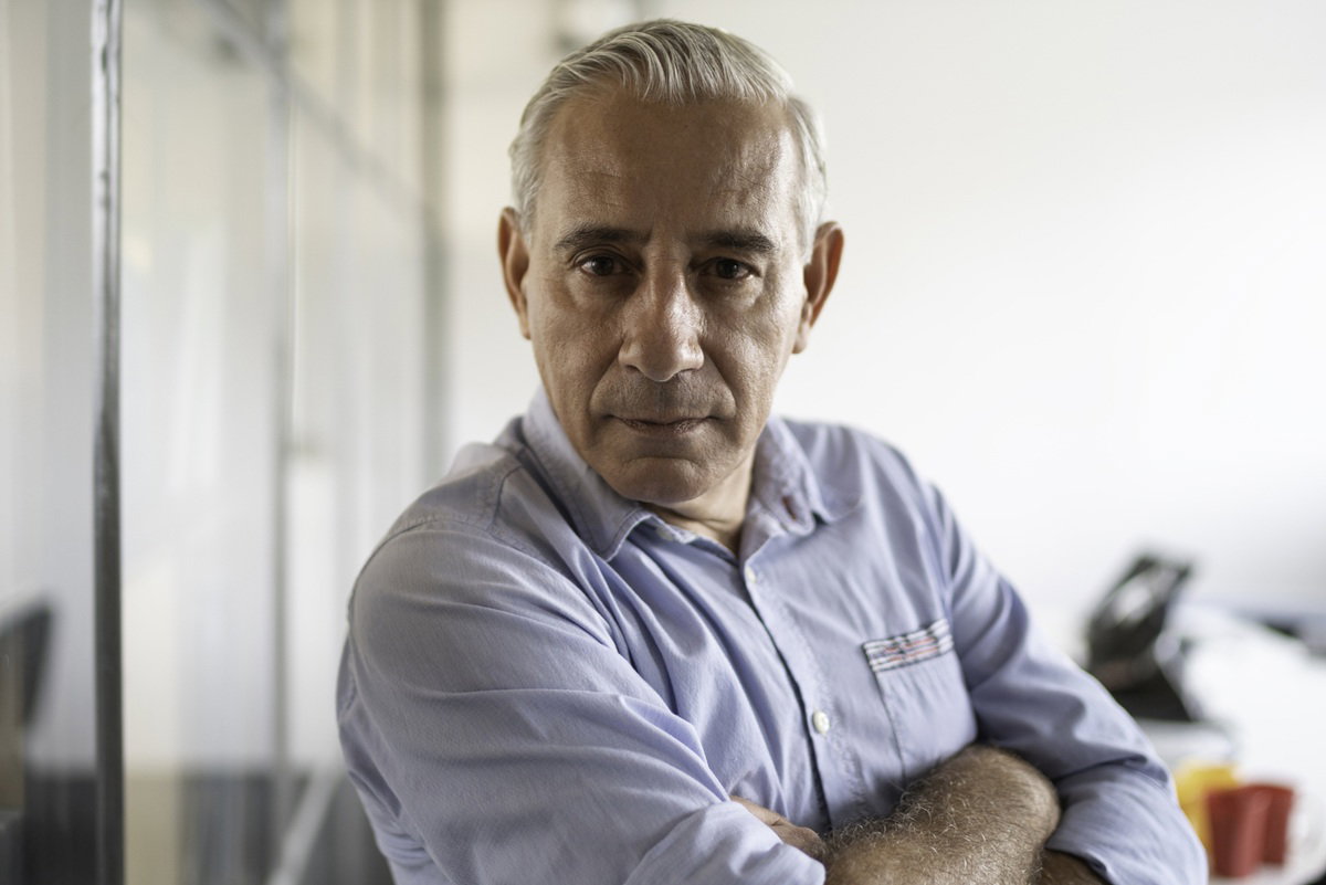 mężczyzna w wieku 55 plus siwy w koszuli w biurze stoi z poważną miną