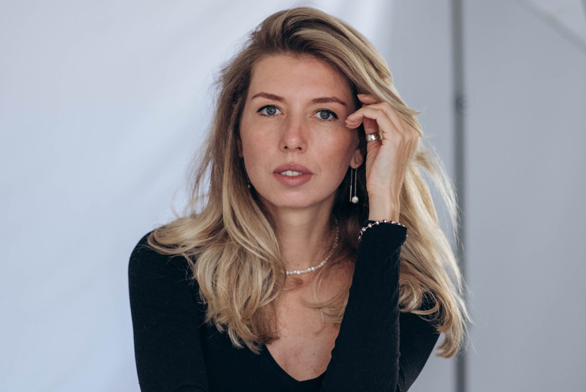 kobieta blondynka w wieku 30 plus w czarnej bluzce siedzi zamyślona