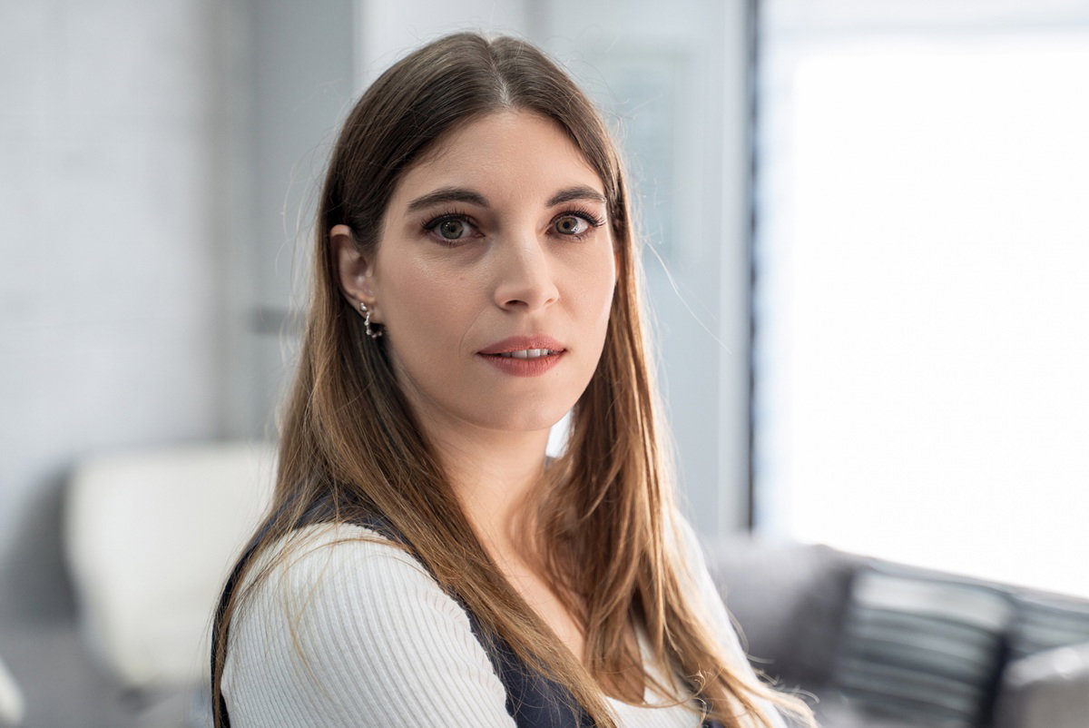 kobieta w wieku 30 plus z długimi włosami stoi w biurze z poważną miną