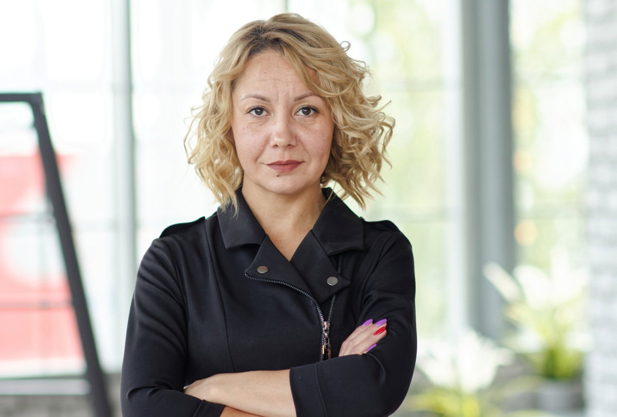 kobieta w wieku 40 plus blondynka w czarnej sukience w stylu rockowym stoi z poważną miną