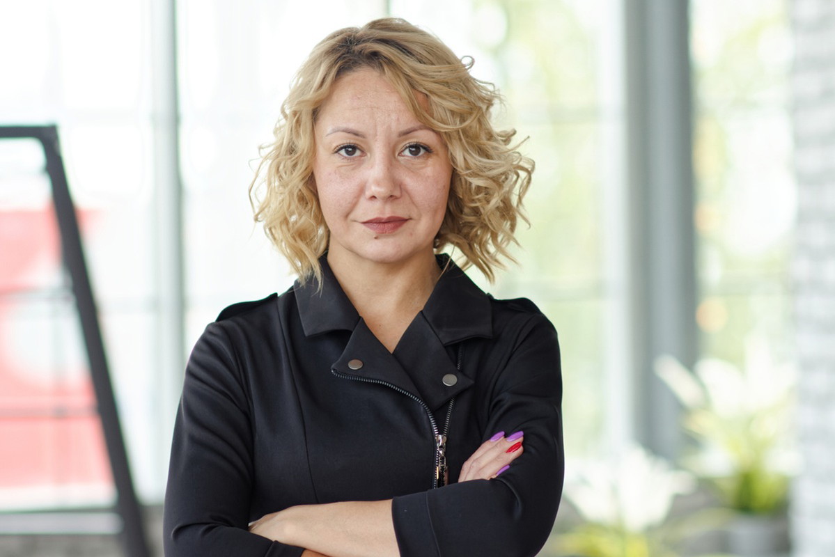kobieta w wieku 40 plus blondynka w czarnej sukience w stylu rockowym stoi z poważną miną