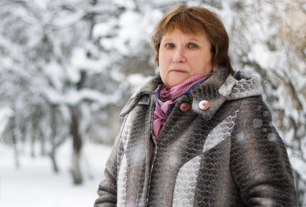 kobieta w wieku 60 plus na tle zimowego pejzażu stoi smutna i zmartwiona