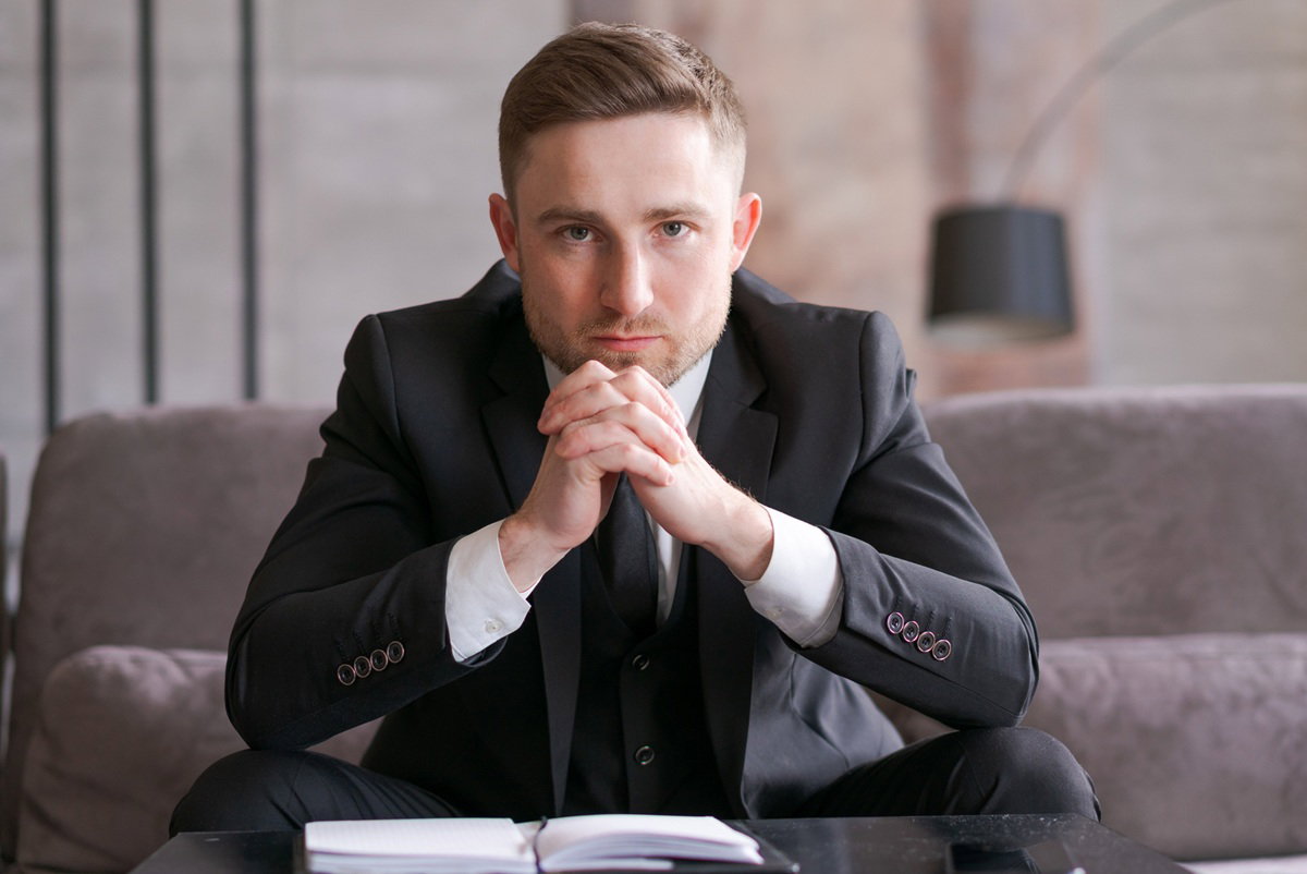 mężczyzna w wieku 30 plus w garniturze siedzi na kanapie zmartwiony