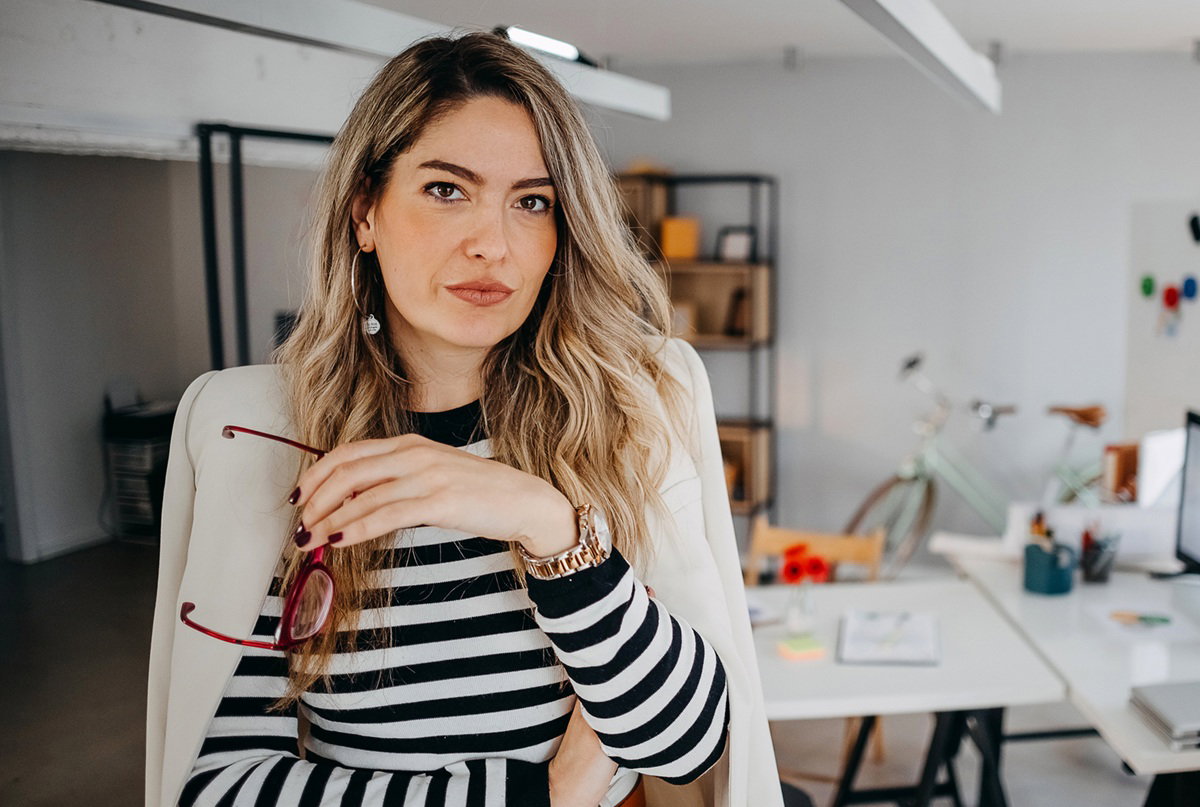 kobieta w wieku 30 plus blondynka w bluzce w paski stoi w swoim biurze z poważną miną