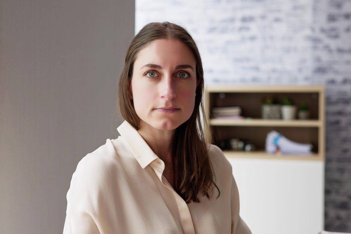 kobieta w wieku 30 plus w jasnej bluzce z dłuższymi włosami siedzi w salonie smutna