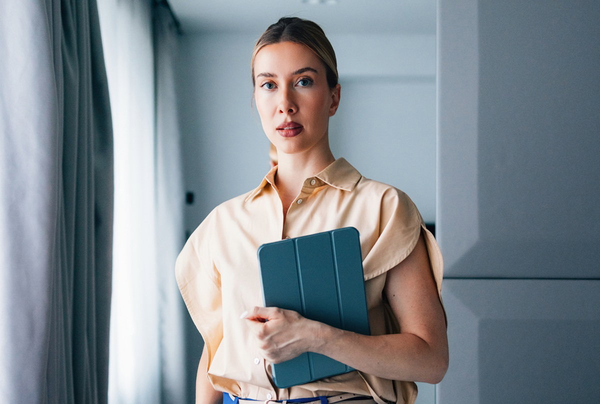 kobieta w wieku 30 plus blondynka stoi z tabletem zamyślona i poważna