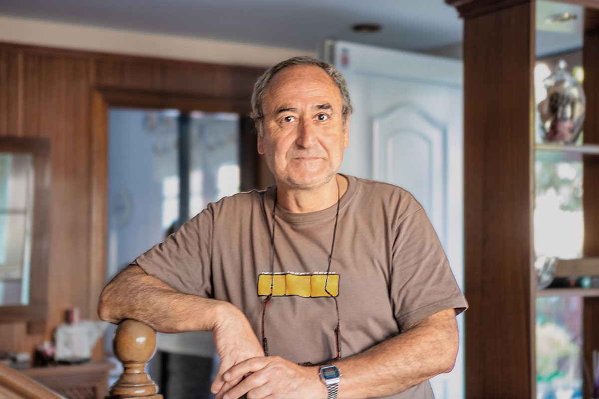 mężczyzna w wieku 65 plus w brązowym t-shircie na tle pokoju stoi zamyślony