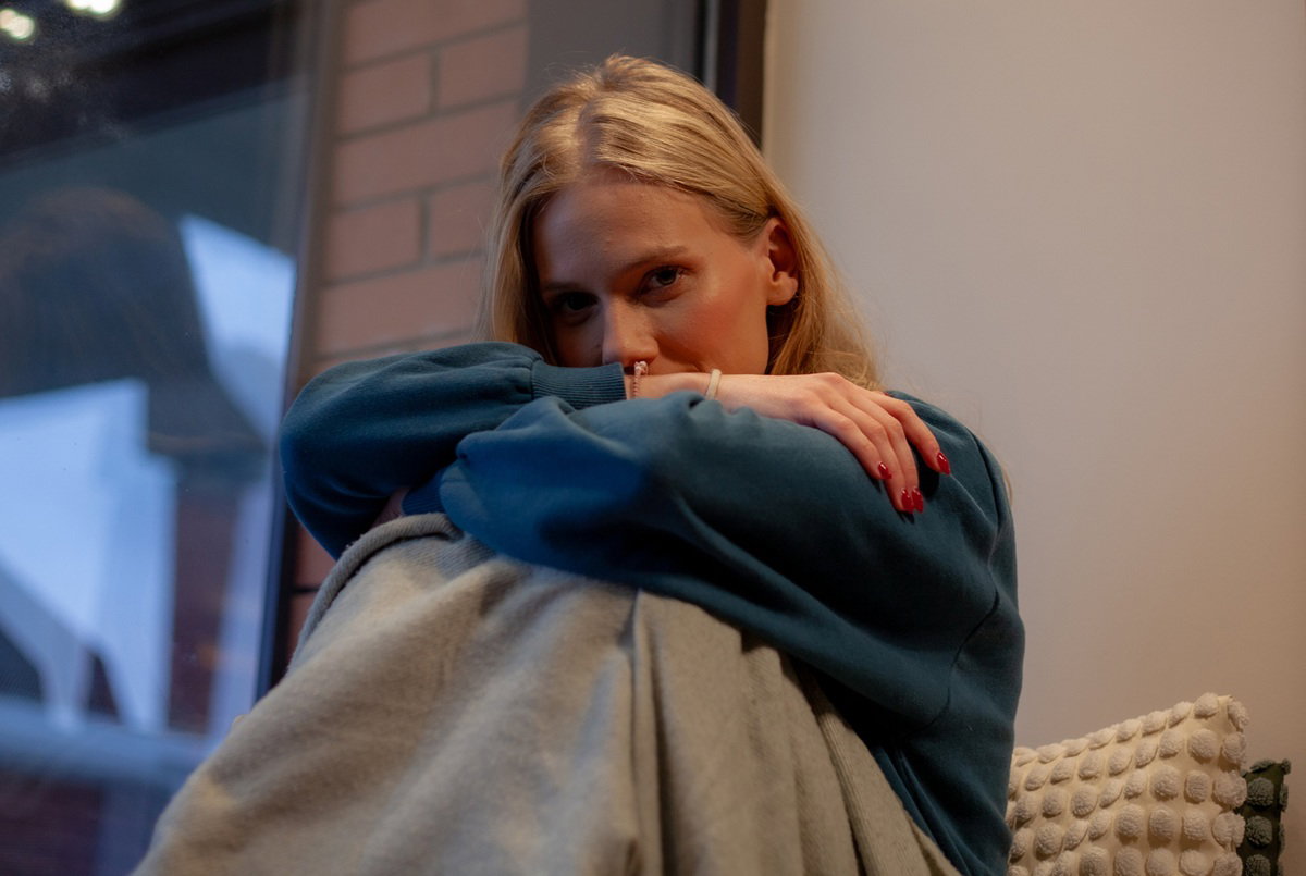 kobieta w wieku 25 plus blondynka siedzi na tarasie pod kocem zamyślona