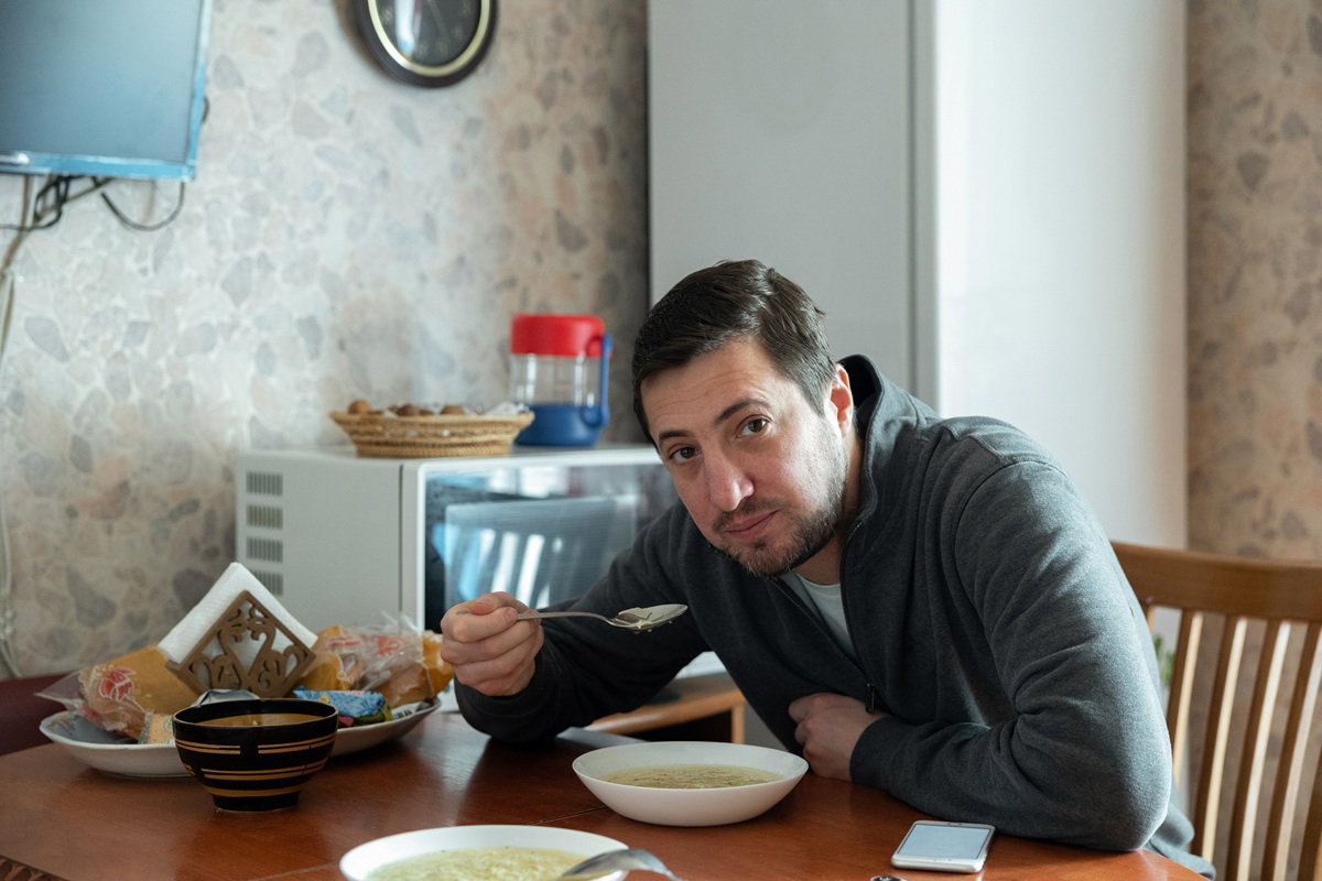 mężczyzna w wieku 35 plus siedzi przy stole i je rosół ze smutną miną