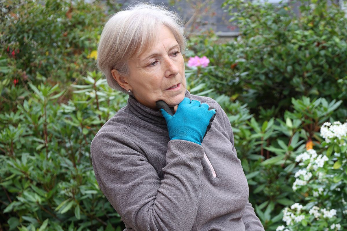 Zamyślona starsza kobieta w ogrodzie