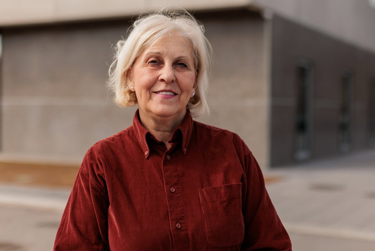 kobieta w wieku 60 plus blondynka w sztruksowej koszuli stoi na zewnątrz i się uśmiecha