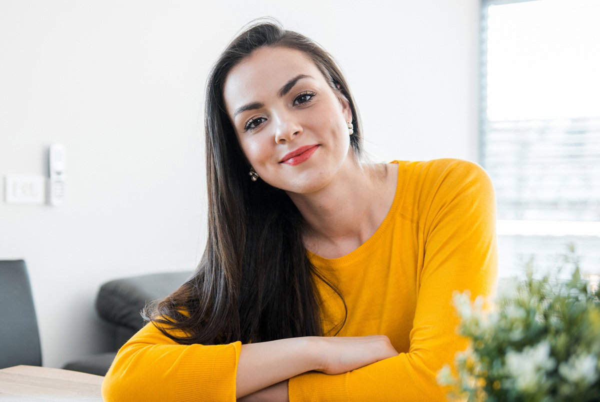 kobieta w wieku 25 plus w żółtej bluzce siedzi przy stole i się uśmiecha