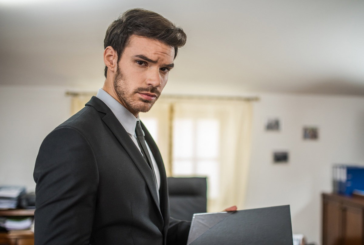 mężczyzna w wieku 25 plus z zarostem z dokumentami w ręce stoi zmartwiony