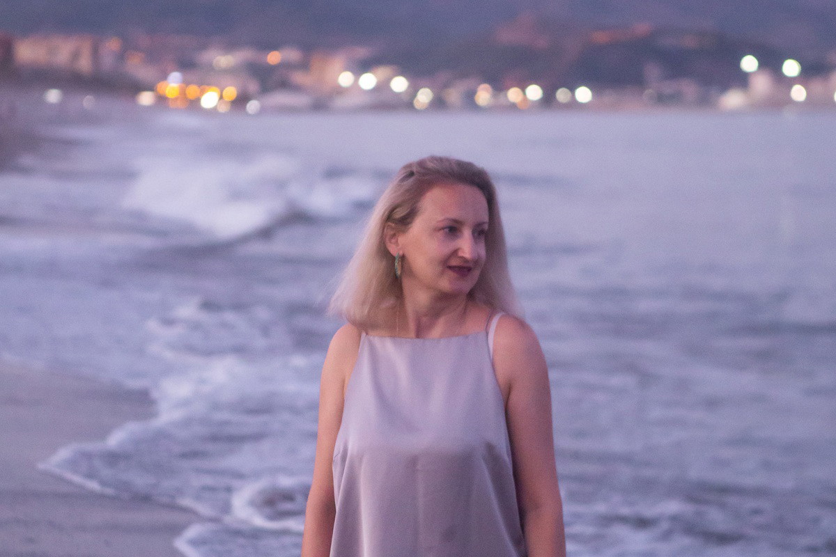 kobieta w wieku 35 plus stoi wieczorem na plaży Costa del Sol w Maladze w Hiszpanii zachwycona