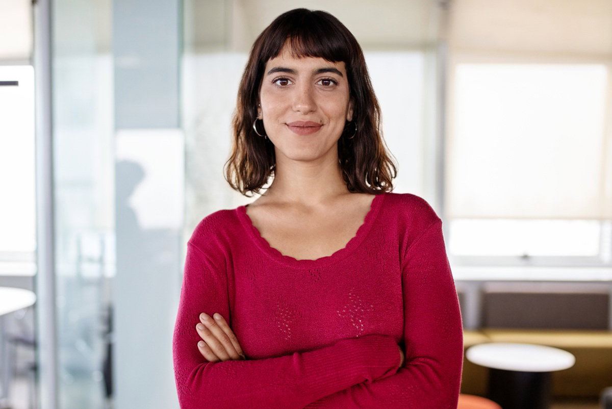 kobieta w wieku 30 plus w czerwonej sukience stoi pewna siebie na tle biura