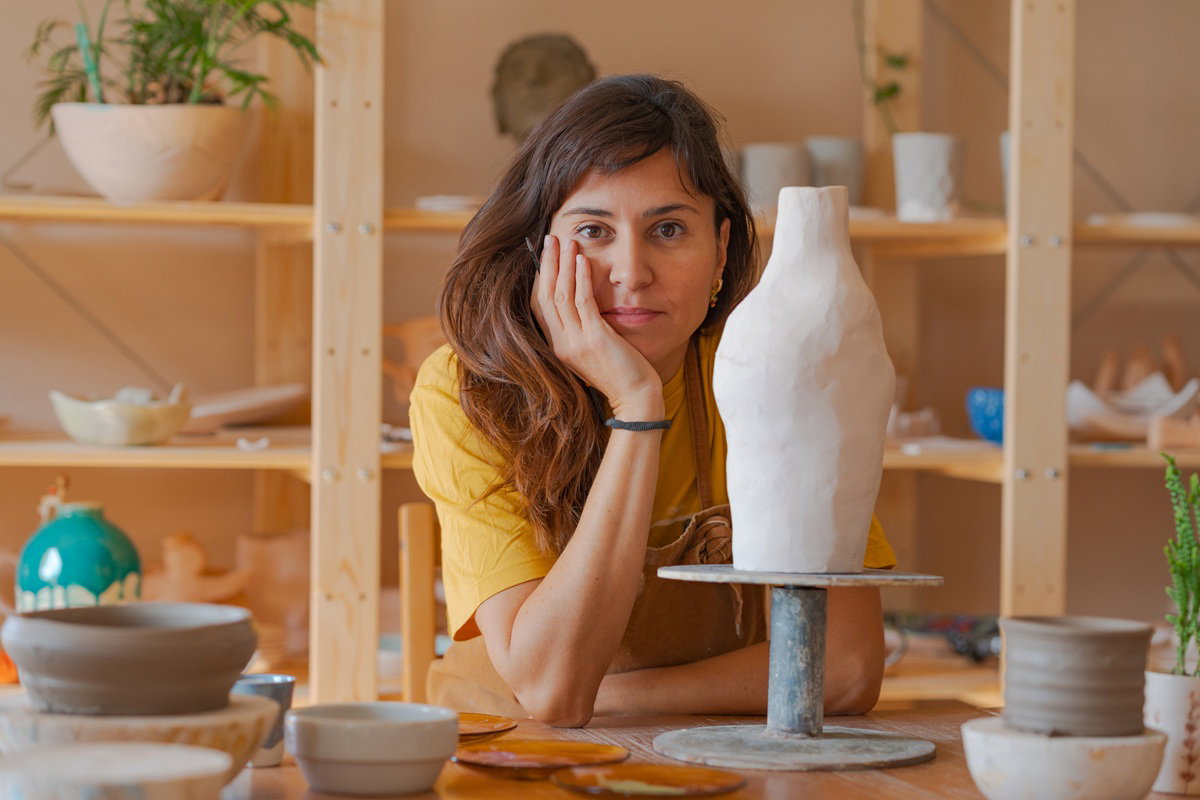 kobieta w wieku 40 plus w pracowni garncarskiej stoi zamyślona