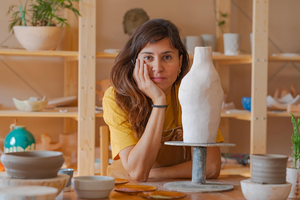 kobieta w wieku 40 plus w pracowni garncarskiej stoi zamyślona