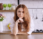 Caucasian female with her glasses in hand worried in a kitchen