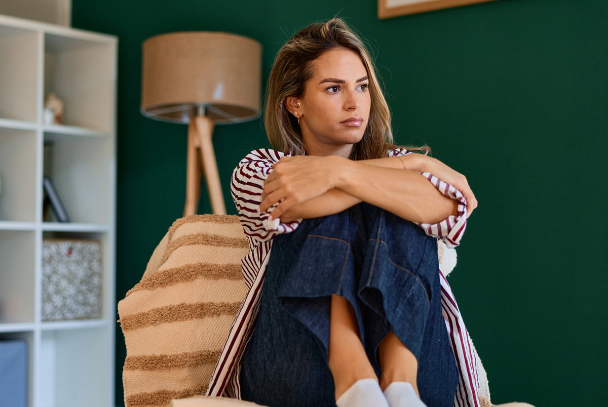 kobieta w wieku 30 plus blondynka siedzi na fotelu w salonie zamyślona