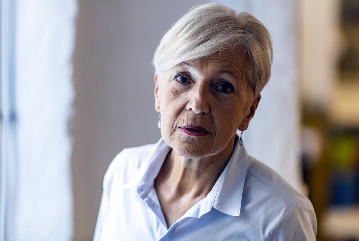 kobieta w wieku 65 plus w krótkiej fryzurze i jasnej koszuli patrzy załamana przed siebie
