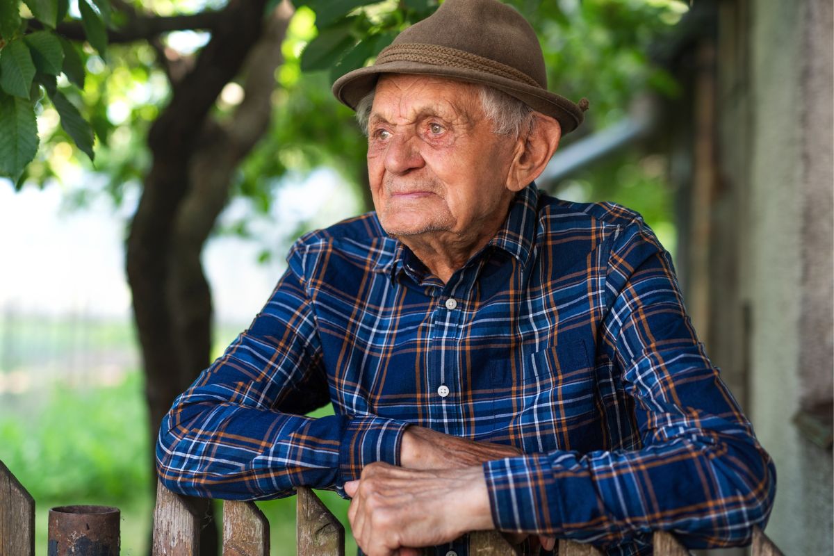 Zamyślony starszy mężczyzna w ogrodzie