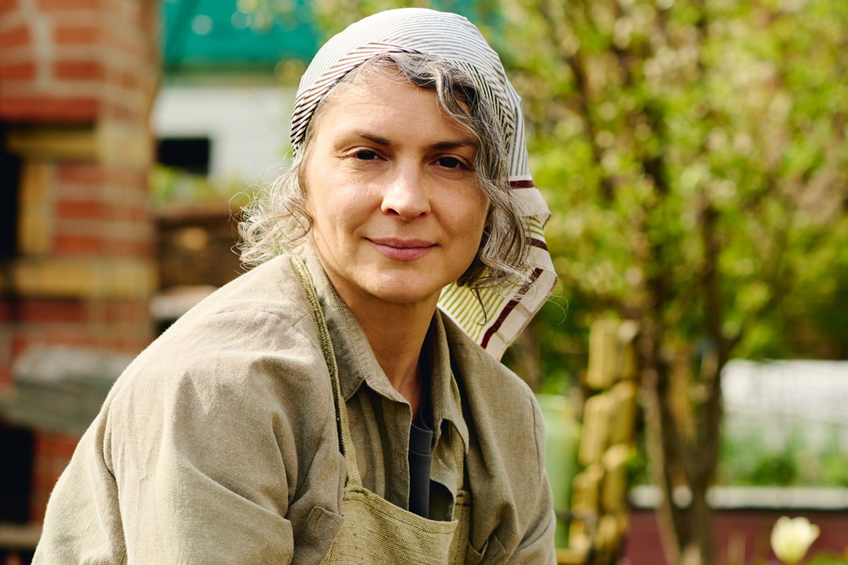 kobieta w wieku 40 plus w chustce na głowie porządkuje ogród