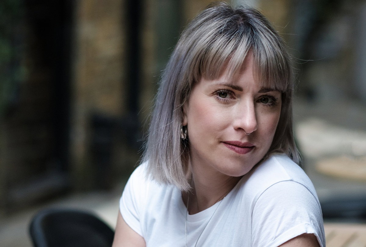 kobieta w wieku 35 plus blondynka w białym t-shircie siedzi w kawiarni zamyślona