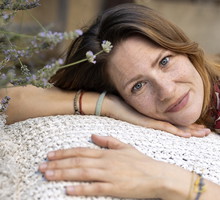 kobieta w wieku 40 plus leży na poduszce na balkonie koło lawendy i lekko się uśmiecha