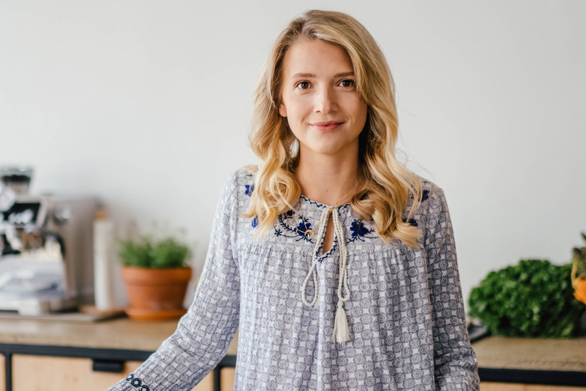 kobieta w wieku 30 plus blondynka stoi w kuchni i lekko się uśmiecha