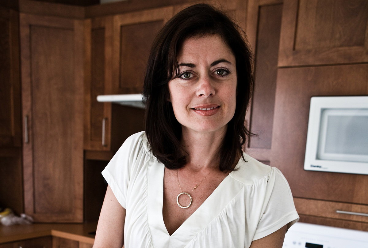 kobieta w wieku 40 plus z ciemnymi włosami stoi w kuchni i przekornie się uśmiecha