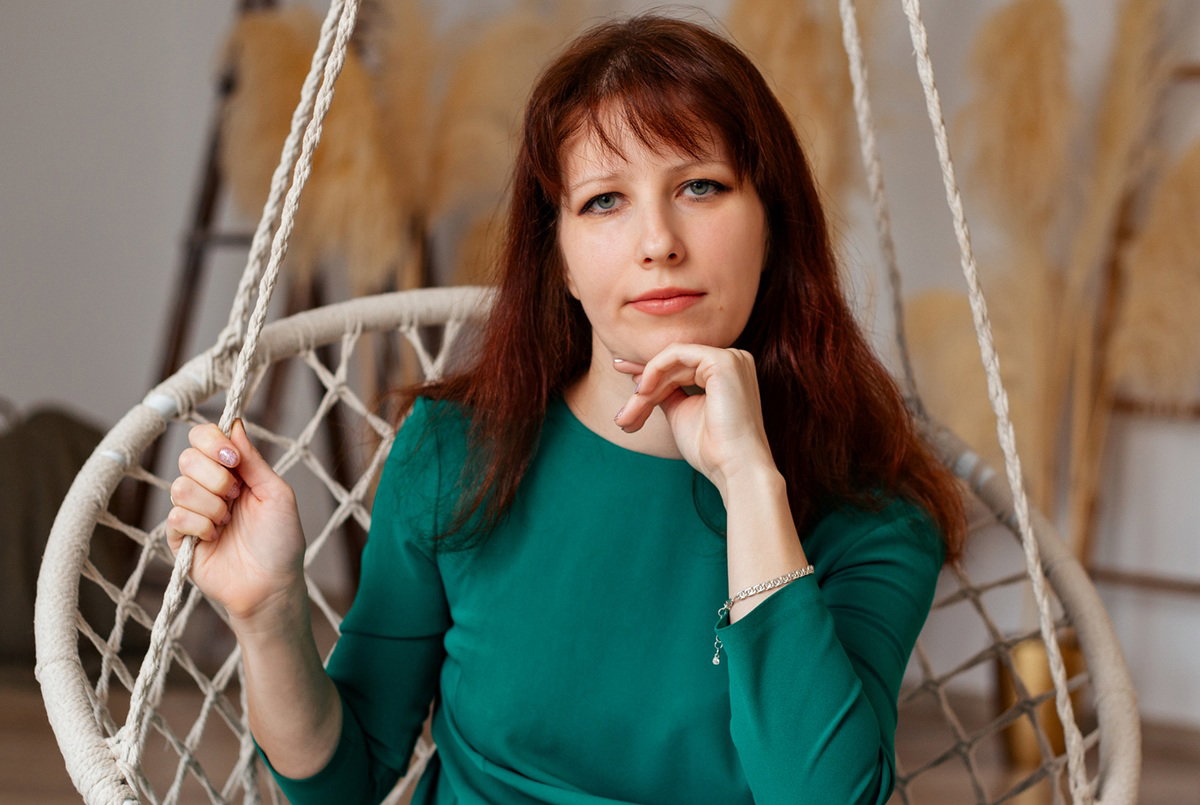 kobieta w wieku 35 plus w zielonej sukience siedzi na huśtawce zniesmaczona i zamyślona