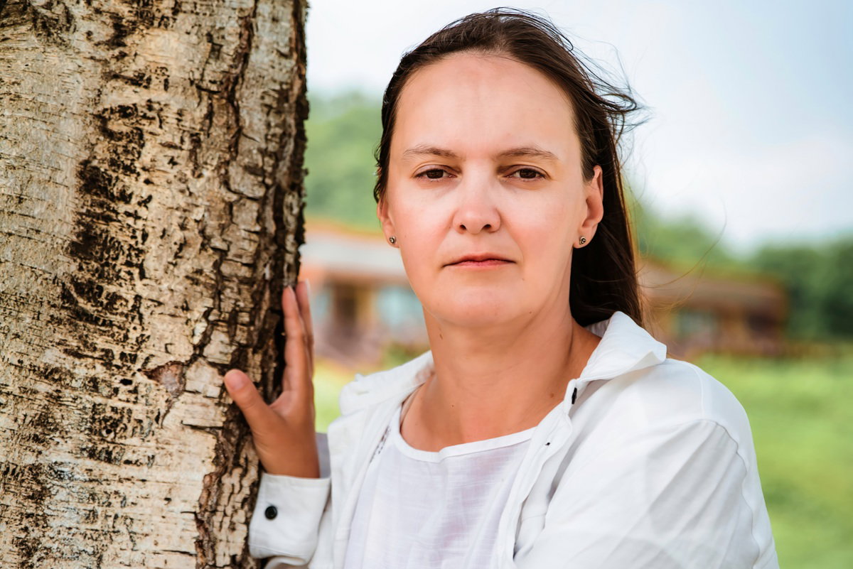 kobieta w wieku 40 plus w jasnej koszuli stoi na wietrze smutna i zamyślona