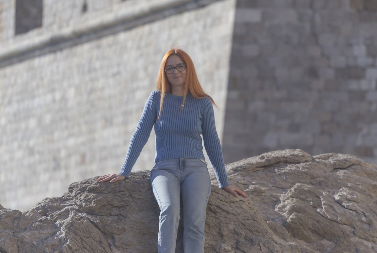 kobieta w wieku 40 plus siedzi nad Adriatykiem blisko starego miasta w Dubrovniku w Chorwacji