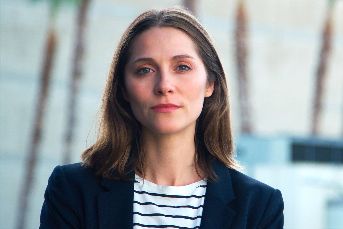 kobieta w wieku 35 plus w marynarce stoi zamyślona na tle biura