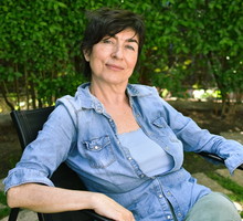 kobieta w wieku 50 plus siedzi na tle zieleni w ogrodzie z zadowoloną miną