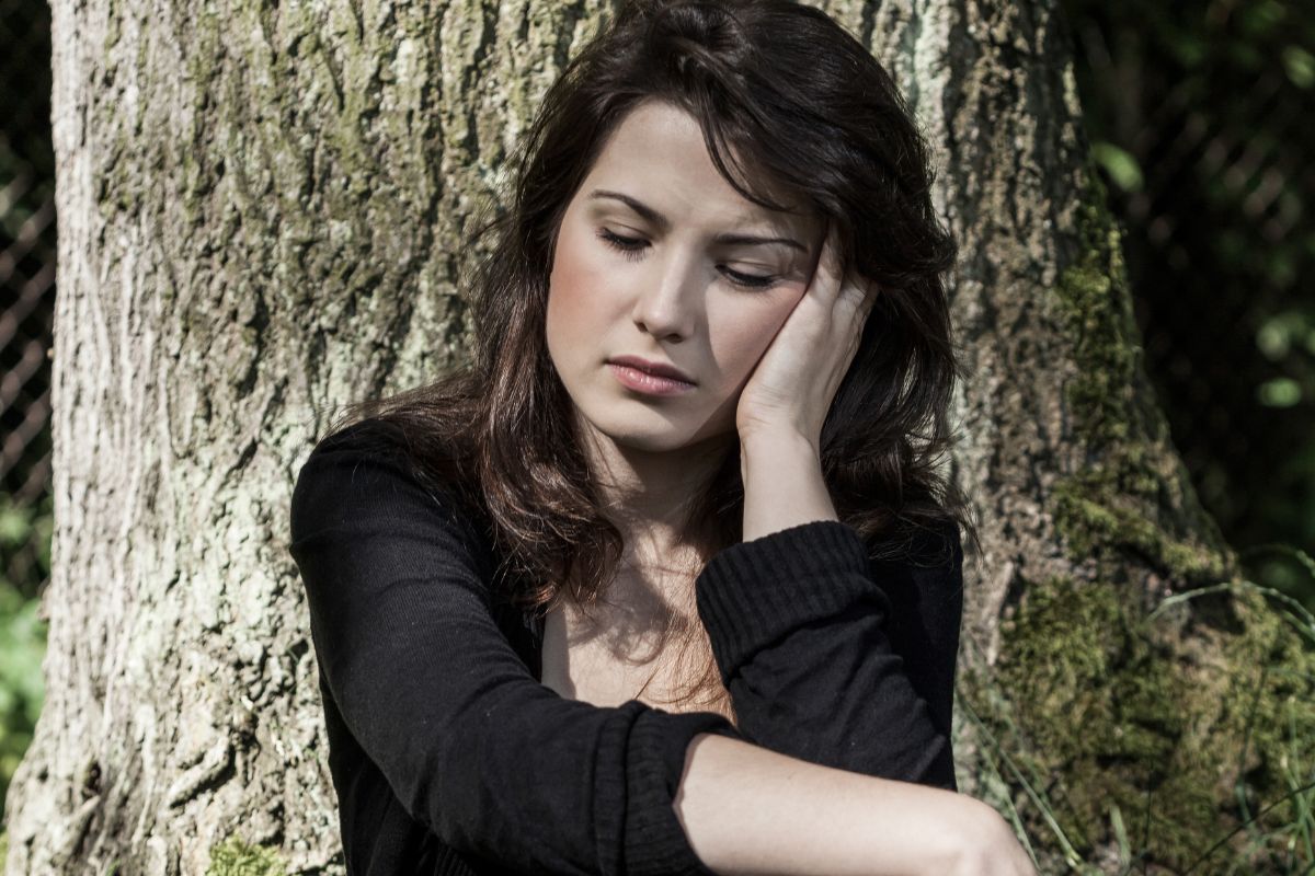Załamana kobieta przy drzewie