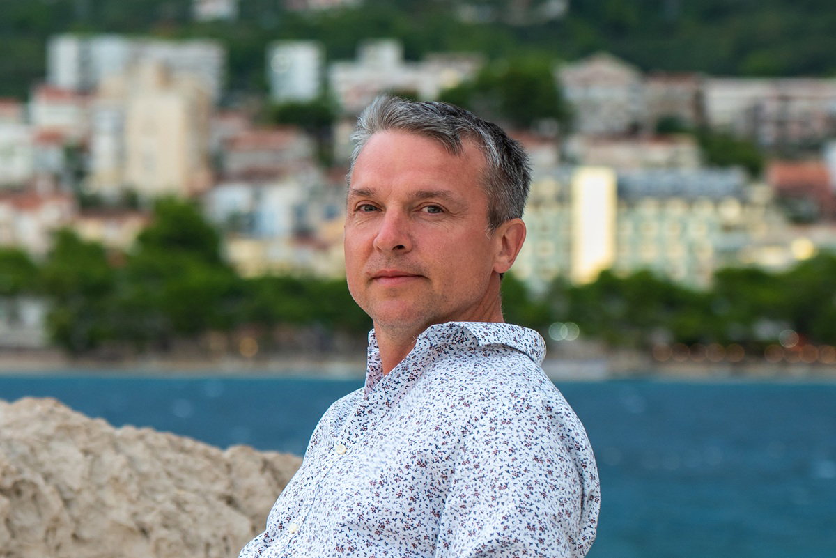 mężczyzna w wieku 45 plus siedzi zamyślony na tle Makarskiej Riviery w Dalmacji