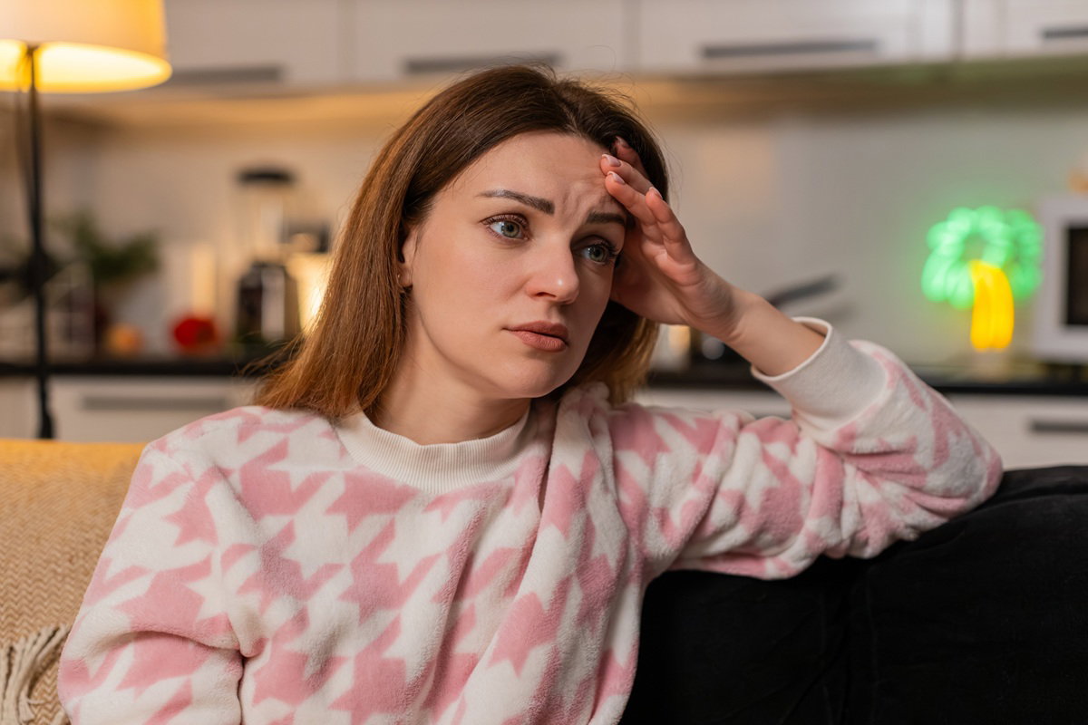 kobieta w wieku 35 plus siedzi na tle kuchni załamana