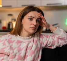 kobieta w wieku 35 plus siedzi na tle kuchni załamana