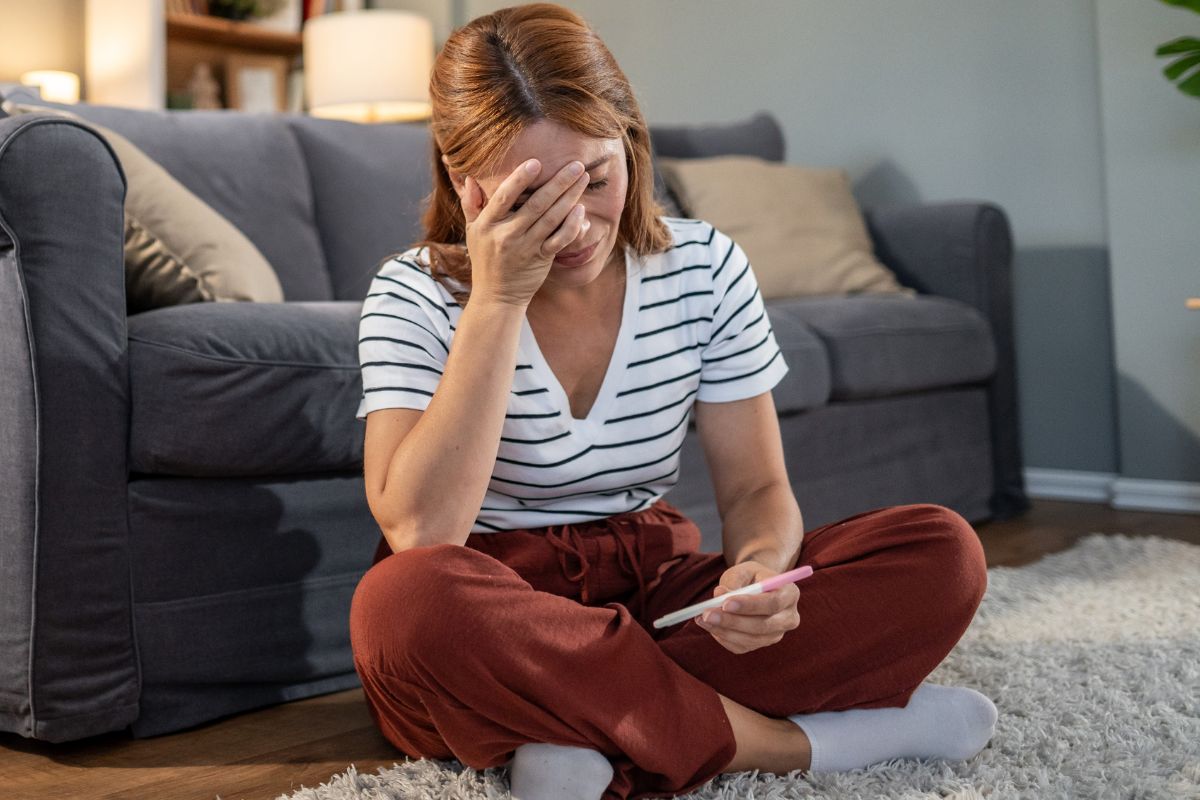 Załamana kobieta z testem ciążowym