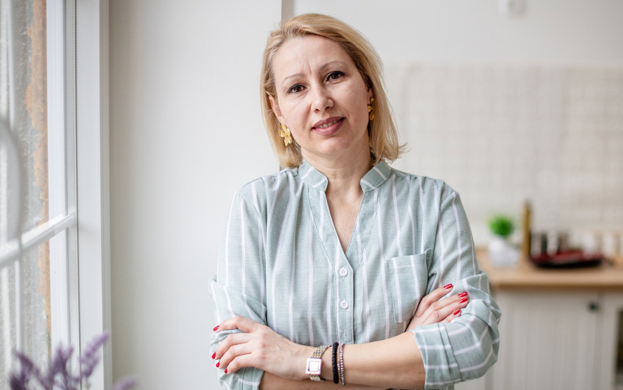 kobieta w wieku 40 plus blondynka w koszuli w paski stoi na tle kuchni z rozczarowaną miną