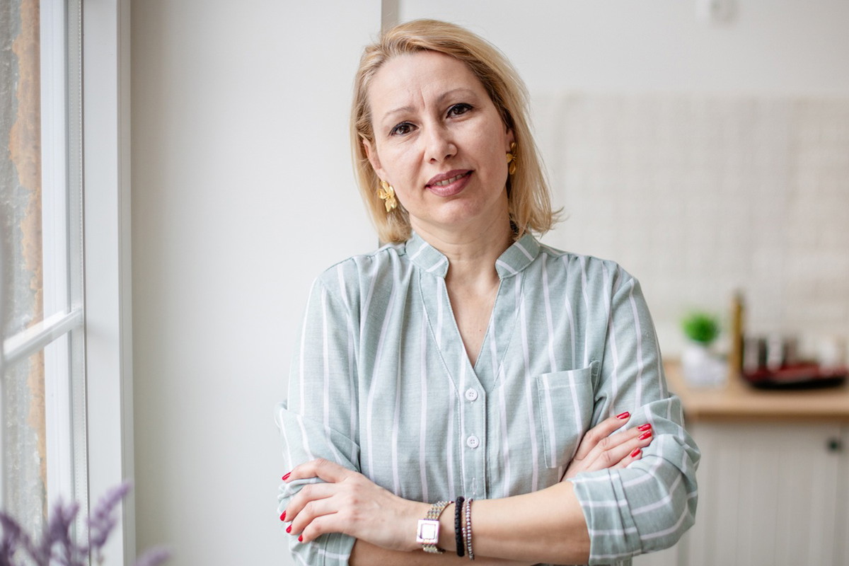 kobieta w wieku 40 plus blondynka w koszuli w paski stoi na tle kuchni z rozczarowaną miną