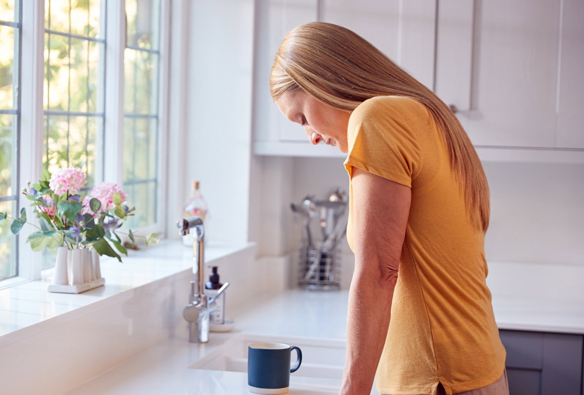 kobieta w wieku 30 plus blondynka w żółtym t-shircie stoi w kuchni załamana