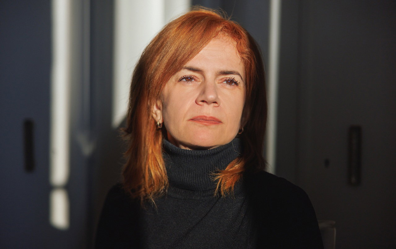 kobieta w wieku 45 plus z rudymi włosami iw  czarnym golfie patrzy w dal zamyślona