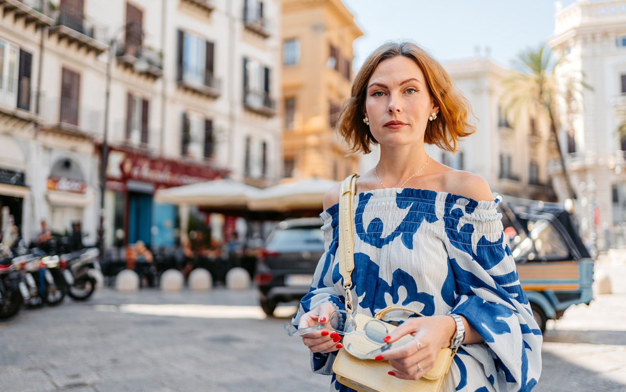 kobieta w wieku 35 plus we wzorzystej sukience stoi smutna w Palermo na Sycylii we Włoszech