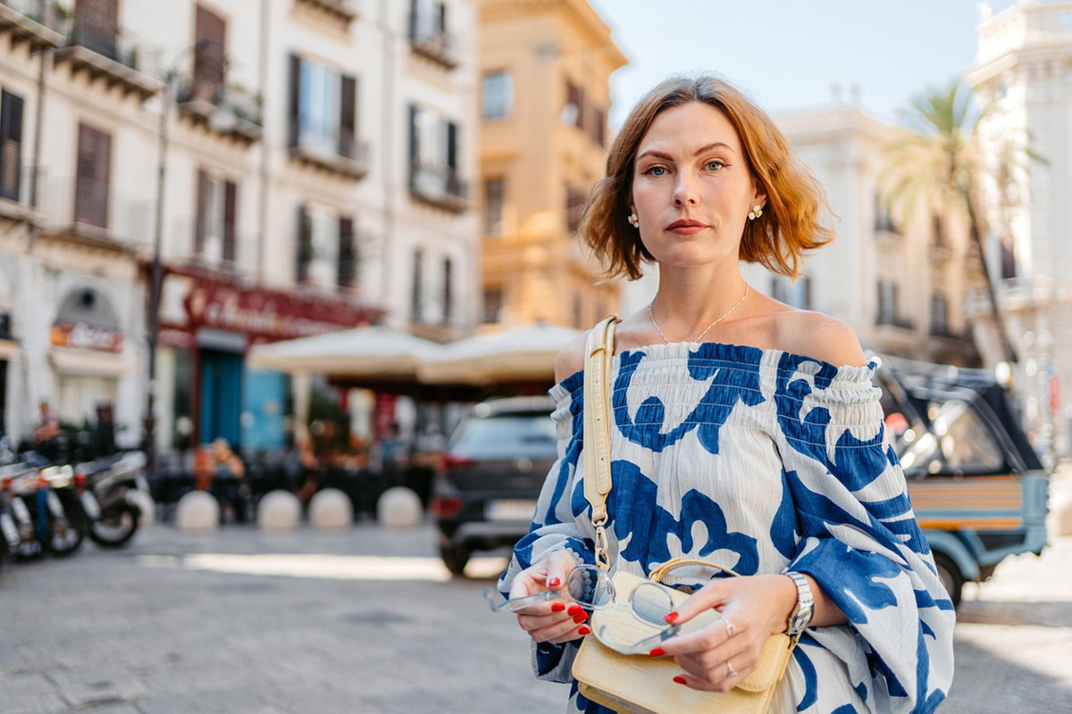 kobieta w wieku 35 plus we wzorzystej sukience stoi smutna w Palermo na Sycylii we Włoszech