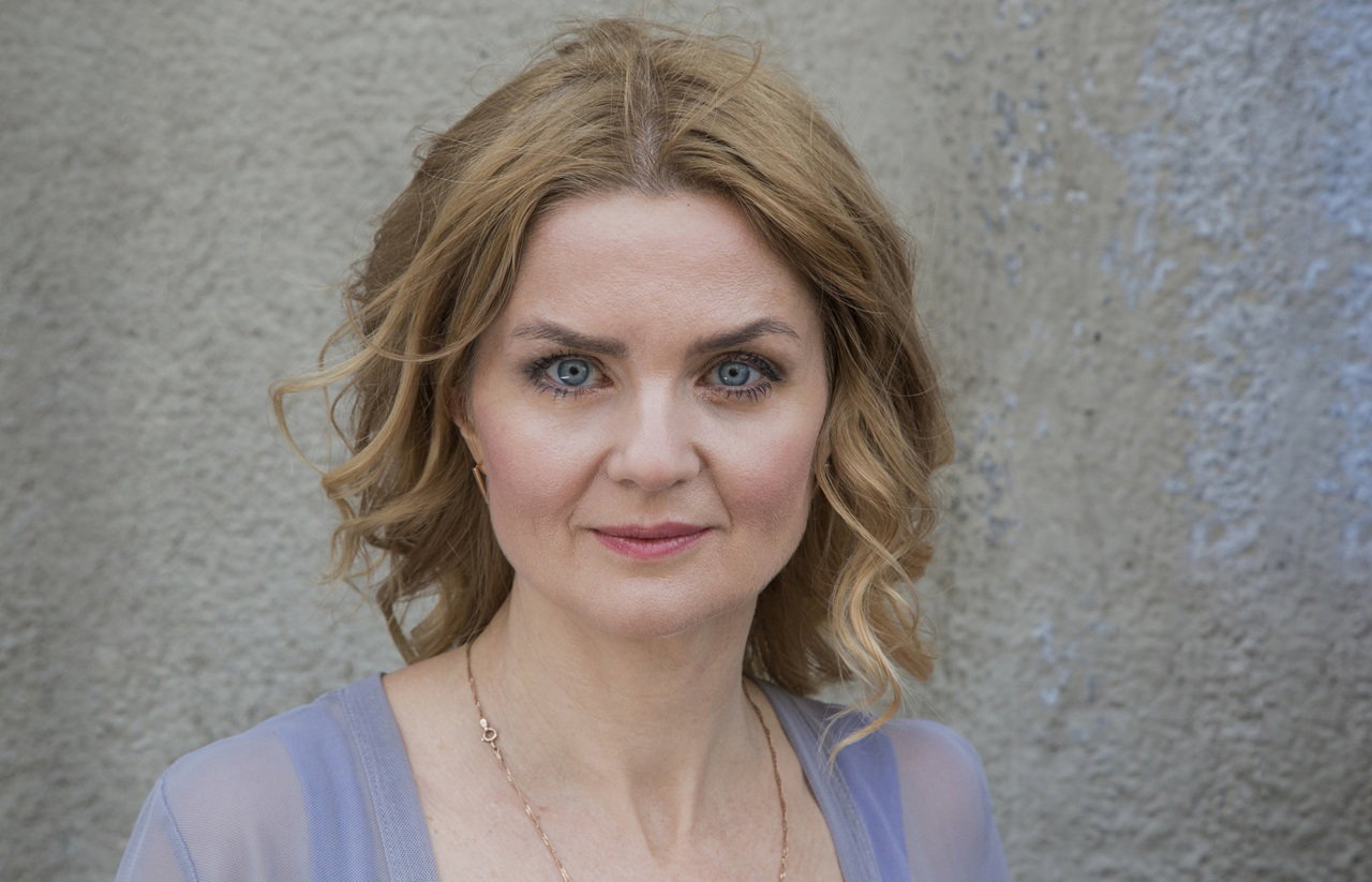 kobieta w wieku 40 plus z falami na włosach i w jedwabnej suknie patrzy przed siebie poważnym wzrokiem